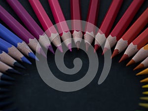 Set of colored pencils arranged in a wheel on slate background