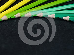 Set of colored pencils arranged in a wheel on slate background