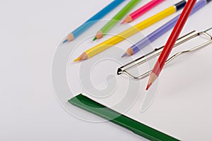 Set of colored pencils and notebook on a white background