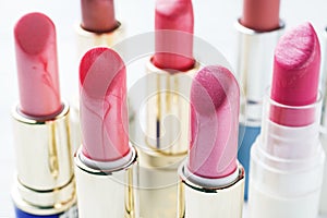 Set of colored pink lipsticks on white background. Women`s cosmetics. Selective focus