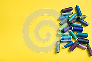 Set of colored thread coils on yellow background, sewing and tailoring
