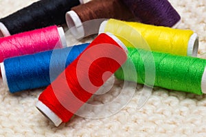 A set of colored threads for sewing on spools. A stack of multi-colored spools of thread