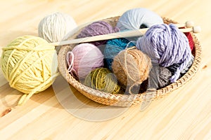 Set of colored yarn balls and needles on straw plate