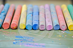 set of colorful chalks lined up on a classroom desk