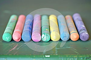 set of colorful chalks lined up on a classroom desk