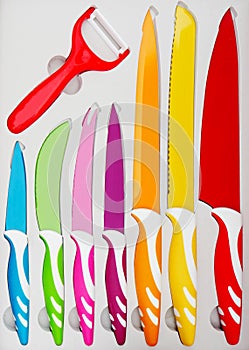 Set of colorful kitchen knives for various uses and a red peeler