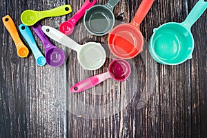 Set of colorful measuring cups and measuring spoons use in cooking lay on dark brown wood tabletop