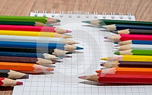 Set of colorful pencils lying in row on white paper