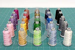 A set of colorful spools of thread on green cutting mat