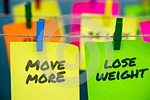 A set of colorful sticky notes with positive affirmation words and phrases hung from a clothesline by clothespins.