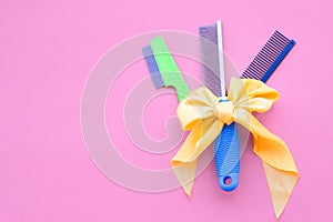 Set of combs tied with a yellow bow and grooming hairdressers on a pink background. Top view, layout, copy space