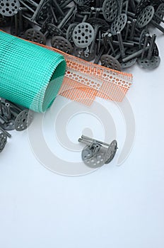 A set of construction items for the insulation of walls. Plastic dowels, a roll of mesh for the insulation of facades and a corne