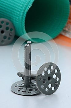 A set of construction items for the insulation of walls. Plastic dowels, a roll of mesh for the insulation of facades and a corne