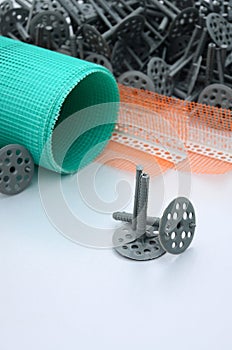 A set of construction items for the insulation of walls. Plastic dowels, a roll of mesh for the insulation of facades and a corne