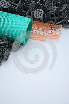 A set of construction items for the insulation of walls. Plastic dowels, a roll of mesh for the insulation of facades and a corne