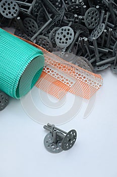 A set of construction items for the insulation of walls. Plastic dowels, a roll of mesh for the insulation of facades and a corne