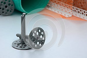 A set of construction items for the insulation of walls. Plastic dowels, a roll of mesh for the insulation of facades and a corne