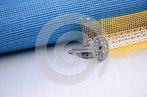 A set of construction items for the insulation of walls. Plastic dowels, a roll of mesh for the insulation of facades and a corner