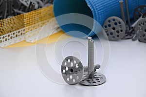 A set of construction items for the insulation of walls. Plastic dowels, a roll of mesh for the insulation of facades and a corner