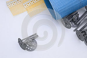 A set of construction items for the insulation of walls. Plastic dowels, a roll of mesh for the insulation of facades and a corner