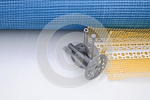 A set of construction items for the insulation of walls. Plastic dowels, a roll of mesh for the insulation of facades and a corner