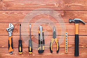 Set of construction tools on a brown wood background. Hammer, wrench, pliers and screwdriver. Frame border, postcard for the