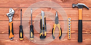 Set of construction tools on a brown wood table. Hammer, wrench, pliers and screwdriver. Postcard for the holiday Labour Day.