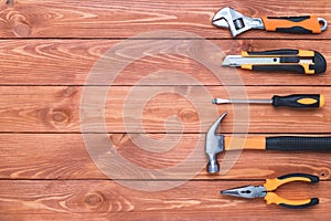Set of construction tools on a brown wooden background. Hammer, wrench, pliers and screwdriver. Frame for the holiday Labor Day,