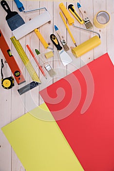 Set of construction tools and colored paper on wooden table