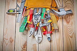 Set of construction tools in toolbelt on wood boards close up