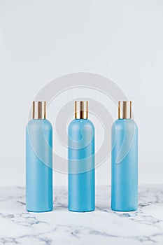 Set of cosmetic bottles, collection of three empty blue bottles of shampoo or lotion on white background