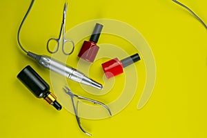 A set of cosmetic tools for manicure and pedicure. Manicure scissors, cuticles, saws, miller stand on a yallow background. Top