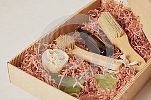 a set of cosmetics and body care products in a box with paper filler, massage oil, gua sha scrapers and a brush