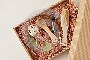 a set of cosmetics and body care products in a box with paper filler, massage oil, gua sha scrapers and a brush