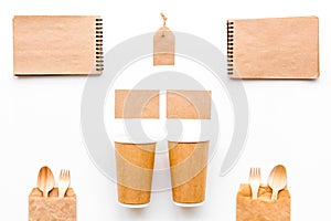 Set of craft bown paper color objects. Paper cup, spoon, fork near label and notebook on white background top view mock