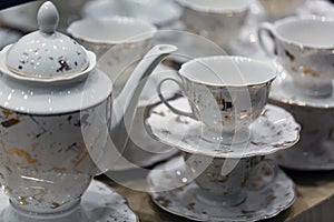 Set cups and teapot on a wooden table. Cups and saucers stacked on top of each other.