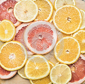 Set of cut citrus fruits lined with lobules on wooden background, top view