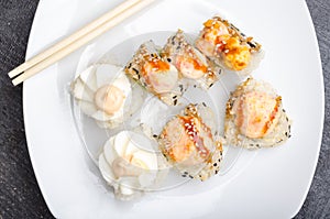 A set of cut japanese sushi rolls and chopsticks on a white plate closeup