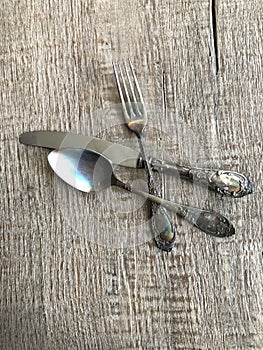 Set of cutlery with fork, knife and spoon on a wooden background.