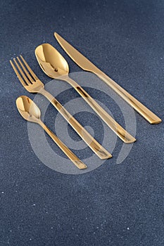 Set of cutlery made of gold metal. Fork, spoon, knife, teaspoon.