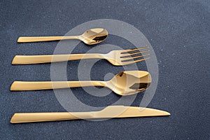 Set of cutlery made of gold metal. Fork, spoon, knife, teaspoon.