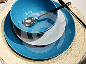 A set of cutlery: a spoon and blue plates on a wooden table. Workpiece on a wooden background.