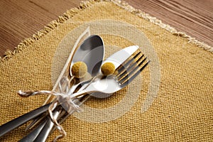 Set of cutlery, yellow cloth and autumnal decor on wooden background. Table setting elements