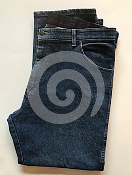 A set of dark jeans folded on a white background