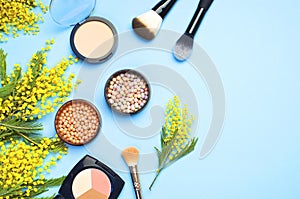 Set of decorative cosmetics for make-up Powder Rouge Eyeshadow Corrector Brushes and flowers of mimosa on blue background. Makeup