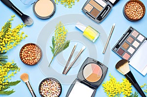 Set of decorative cosmetics for make-up Powder Rouge Eyeshadow Corrector Brushes and flowers of mimosa on blue background. Makeup