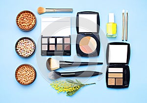 Set of decorative cosmetics for make-up Powder Rouge Eyeshadow Corrector Brushes and flowers of mimosa on blue background. Makeup