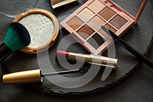 Set of decorative cosmetics, makeup tools and accessories on black slate background. Copy space. Flat lay. Top view. Skin care or