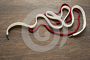 Set of decorative white and red cords on wooden background.