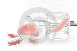 Set of Denture in glass of water and tools on white background